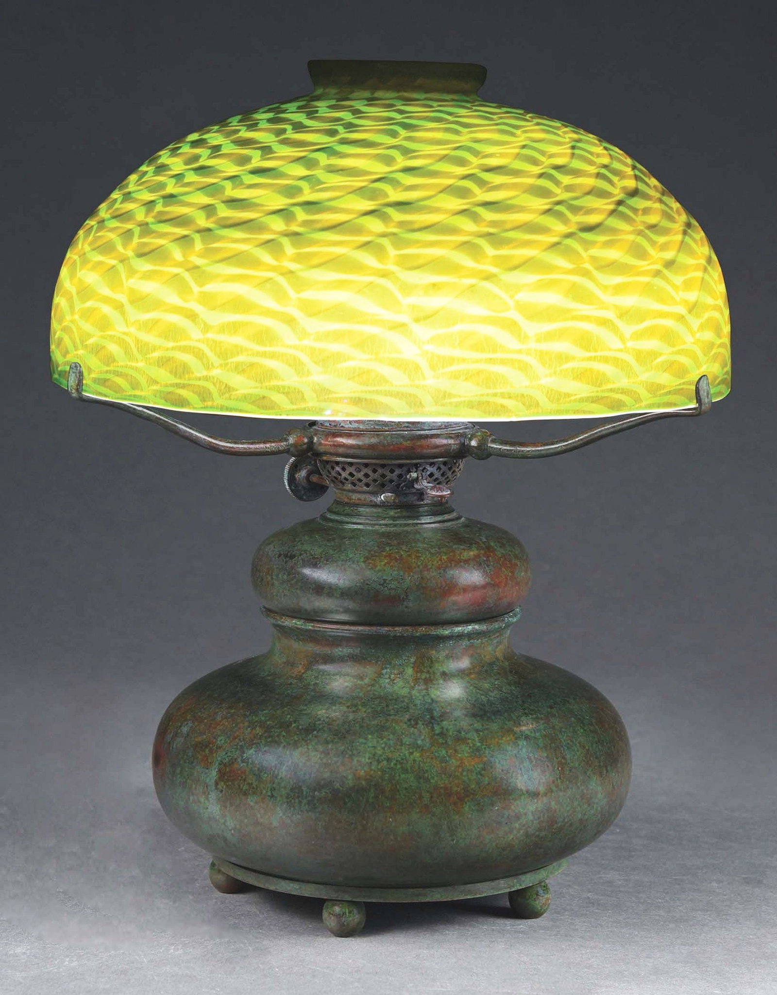 TIFFANY STUDIOS 12" DAMASCENE DESK LAMP.: An absolutely beautiful Favrile glass and patinated bronze desk lamp by Tiffany Studios. The bronze base features a circular bottom with 5 ball feet. The three-arm base has a single socket converted f