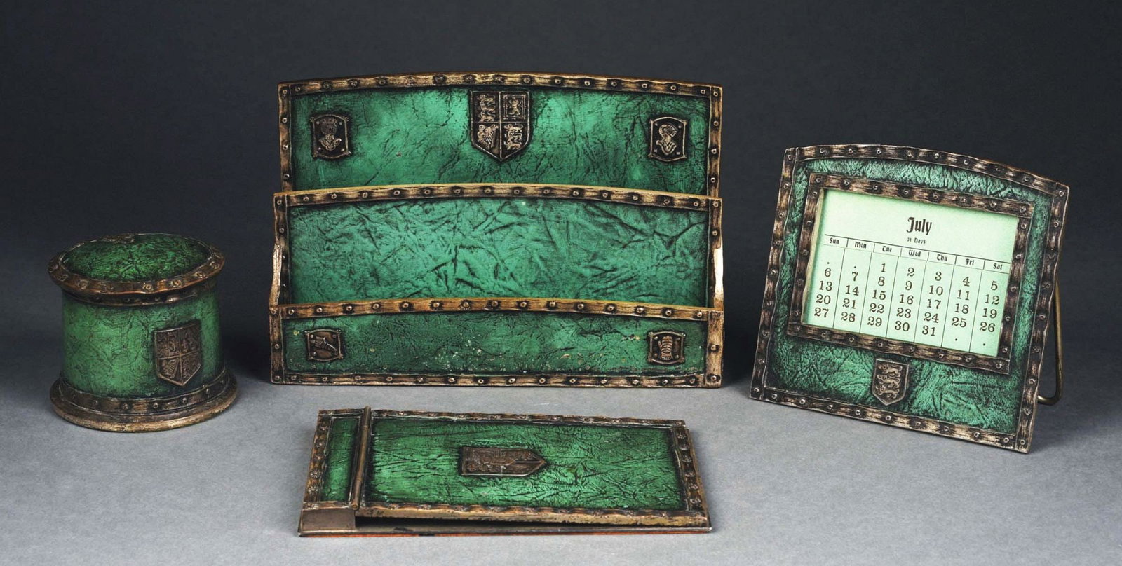 TIFFANY STUDIOS HERALDIC 4-PIECE DESK SET: A lovely four-piece desk set by Tiffany Studios in the very rare Heraldic pattern. Each of the four pieces bears the green Heraldic pattern in this lovely desk set. It includes a notepad (2040), inkwe