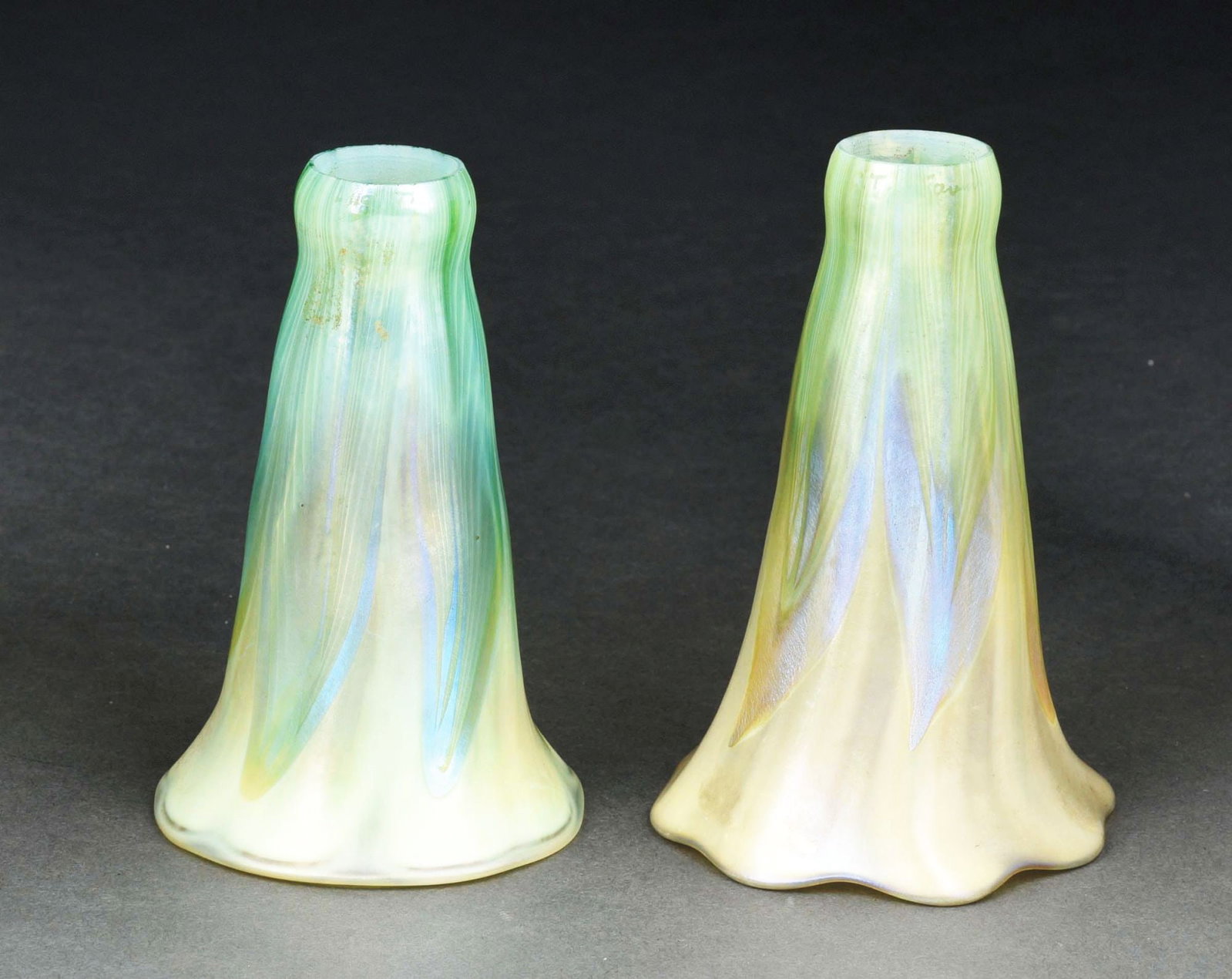LOT OF 2: TIFFANY STUDIOS PULLED FEATHER LILY SHADES.: A beautiful pair of green pulled feather lily shades by Tiffany Studios. Both shades have a frosted green background with slight iridescence, which is further decorated by a green pulled feather patte