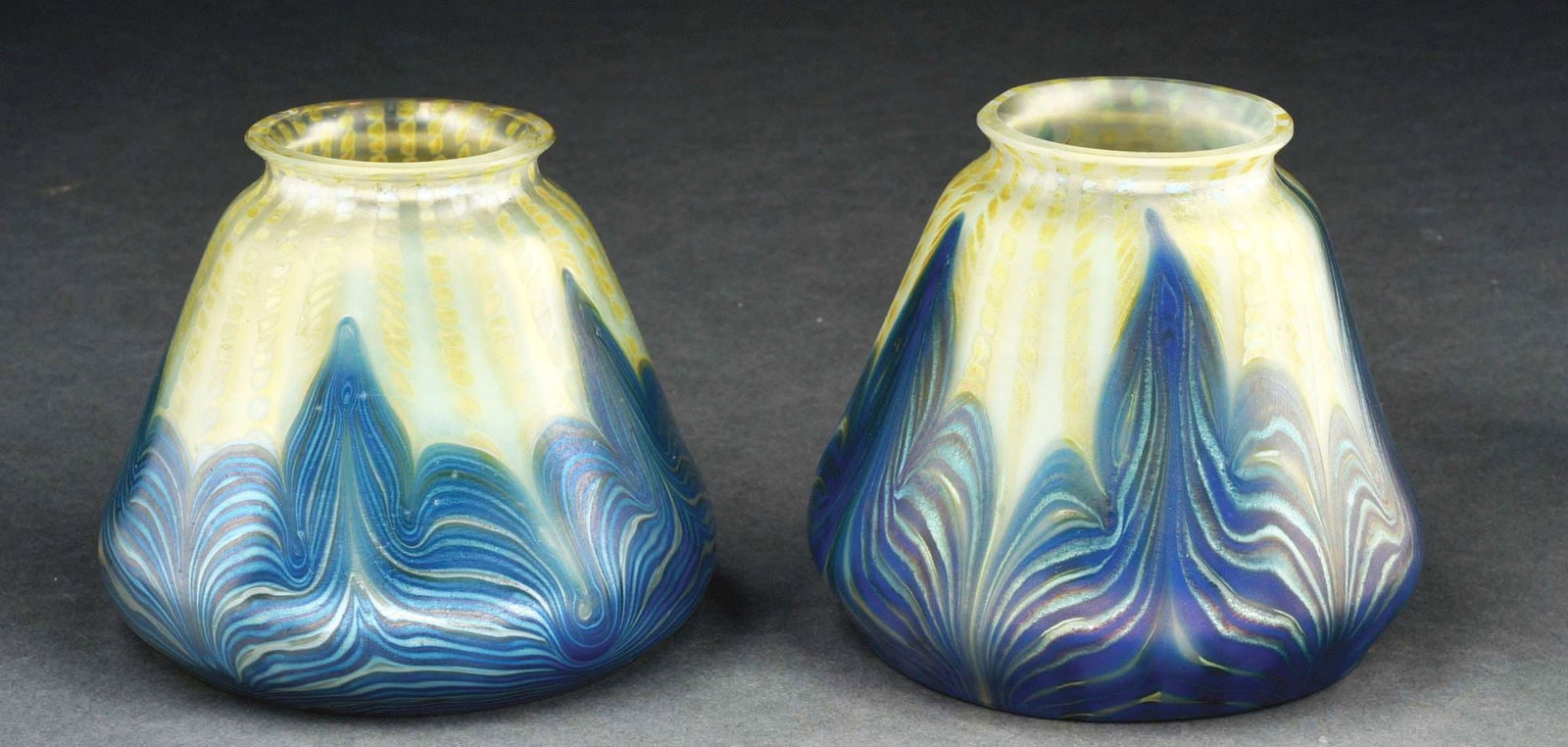 LOT OF 2: ART GLASS SHADES BY LOETZ.: A beautiful pair of early 20th century art glass shades by Loetz. Each shade stands 4" tall and consists of a cream-colored background with iridescent oil spot pattern and swirling blue pattern toward