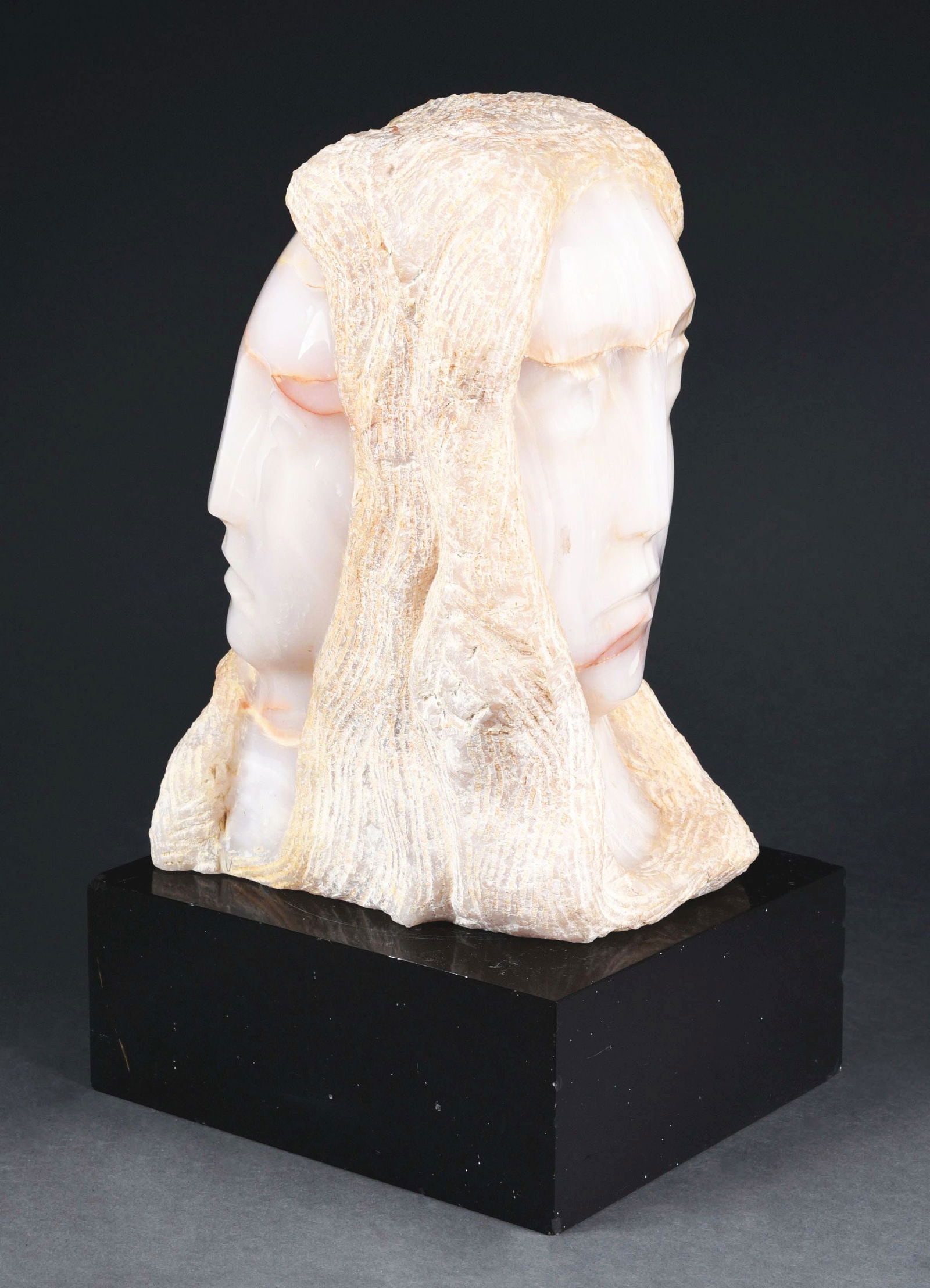 BERNARD SIMON (AMERICAN, 1896-1980) DOUBLE-FACED WOMAN ALABASTER STONE BUST ON MARBLE BASE.: Intricately hand-carved alabaster stone woman bust with double-sided faces on a black marble base. Signed on the neck, "B. Simon". Bernard Simon (American, 1896-1980). This is not a standard shippable
