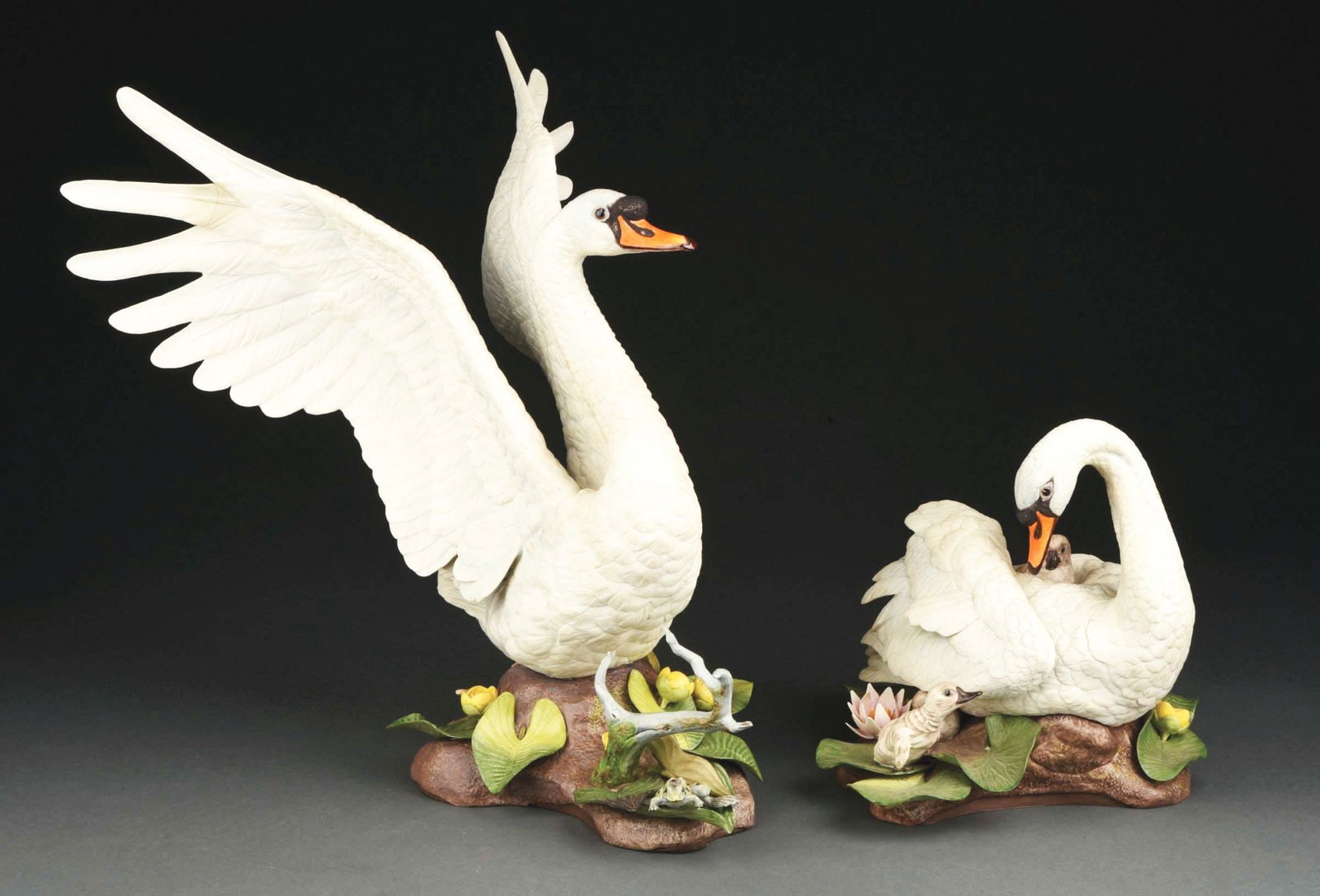 PAIR OF EDWARD BOEHM PORCELAIN MUTE SWANS.: (A) Large swan with glued feather has base with frog and flowers. 20" by 17". (B) The other is a mother swan with cygnet. 12" by 10". Condition: (Very Good - Excellent). Item Dimensions: Largest: 17 -