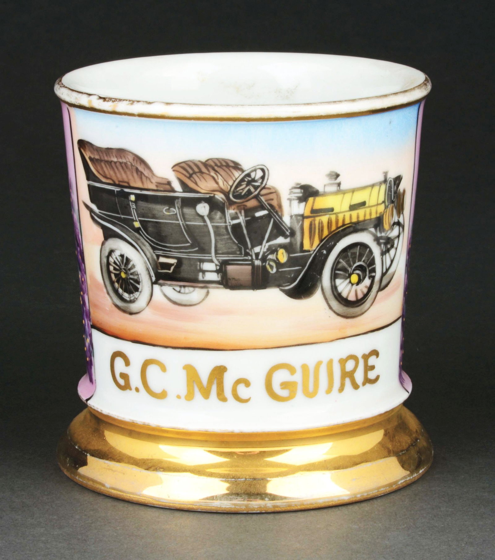 AUTOMOBILE PRODUCER SHAVING MUG.: Has the name "G.C. McGuire" in gold gilt. Comes with pink wrap. Stamped "Germany" under base. Detailed image of an early automobile. Condition: (Excellent). Item Dimensions: 4 - 1/2" x 3 - 1/2" x 3 - 