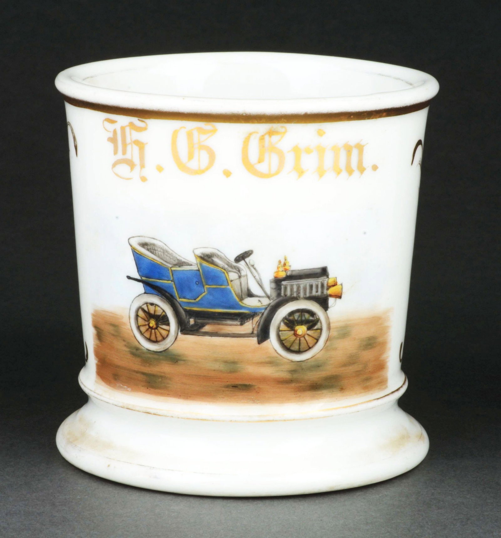 AUTOMOBILE PRODUCER SHAVING MUG: Has the name "H.G. Grim" in gold gilt. Mug is stamped "T&V Limoges France" under base. Detailed image of early automobile. Condition: (Excellent) Item Dimensions: 4 - 1/2" x 3 - 1/2" x 3 - 1/2".