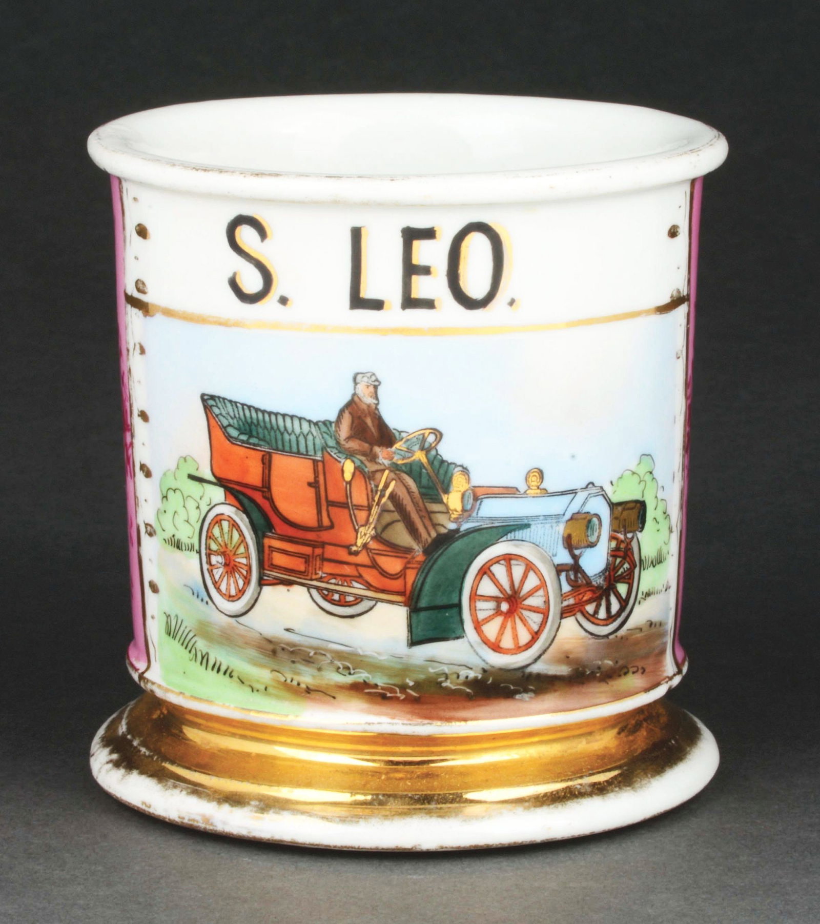 CHAUFFER SHAVING MUG.: Has the name "S. Leo" in black lettering. Pink wrap. Detailed image of chauffer operating early automobile. Condition: (Excellent). Item Dimensions: 4 - 1/2" x 3 - 1/2" x 3 - 1/2".