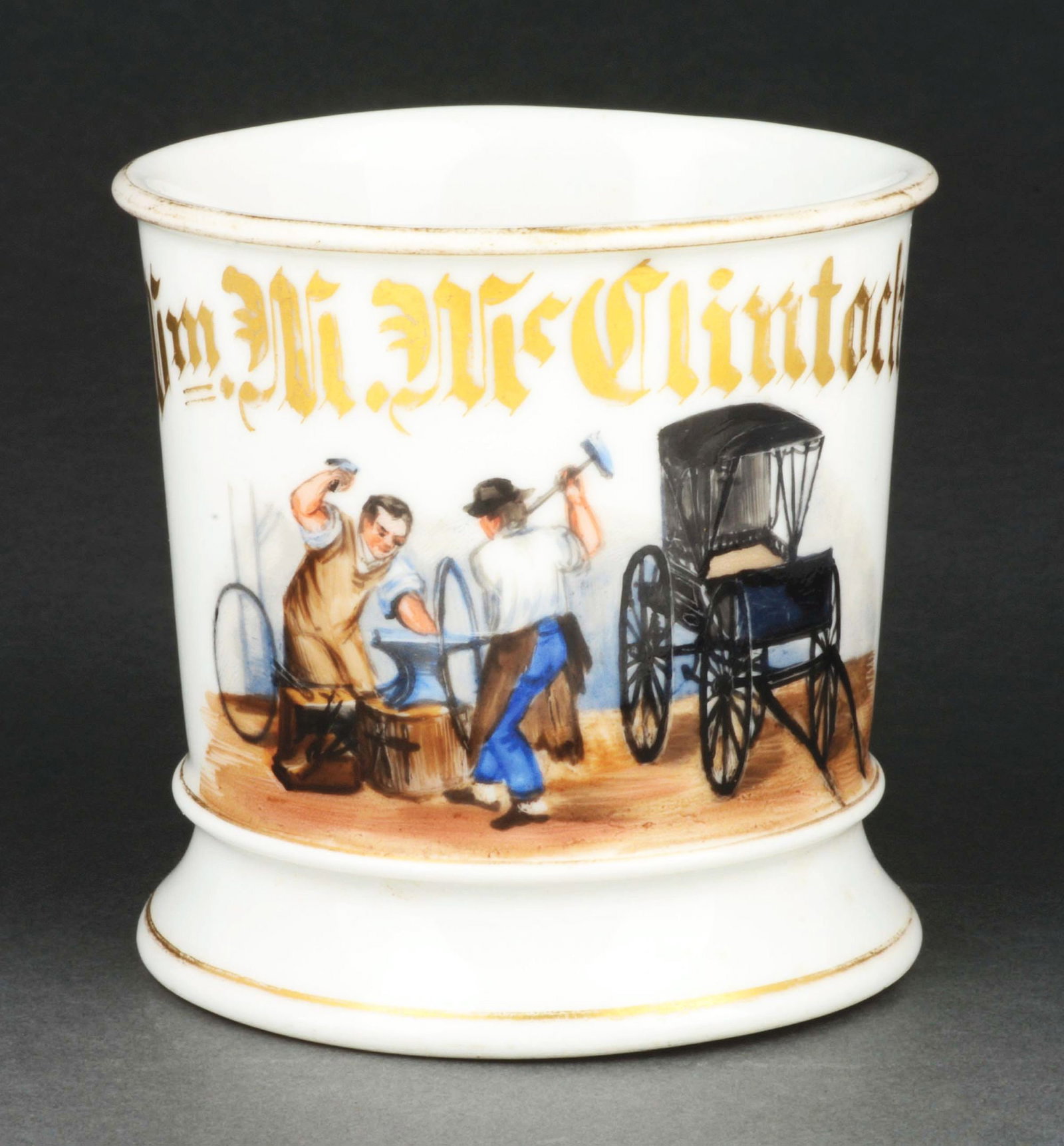 CARRIAGE WHEEL REPAIR SHAVING MUG.: Has the name "William M. McClintock" in gold gilt. Image of two men repairing tires for buggy. Condition: (Excellent). Item Dimensions: 4 - 1/2" x 3 - 1/2" x 3 - 1/2".
