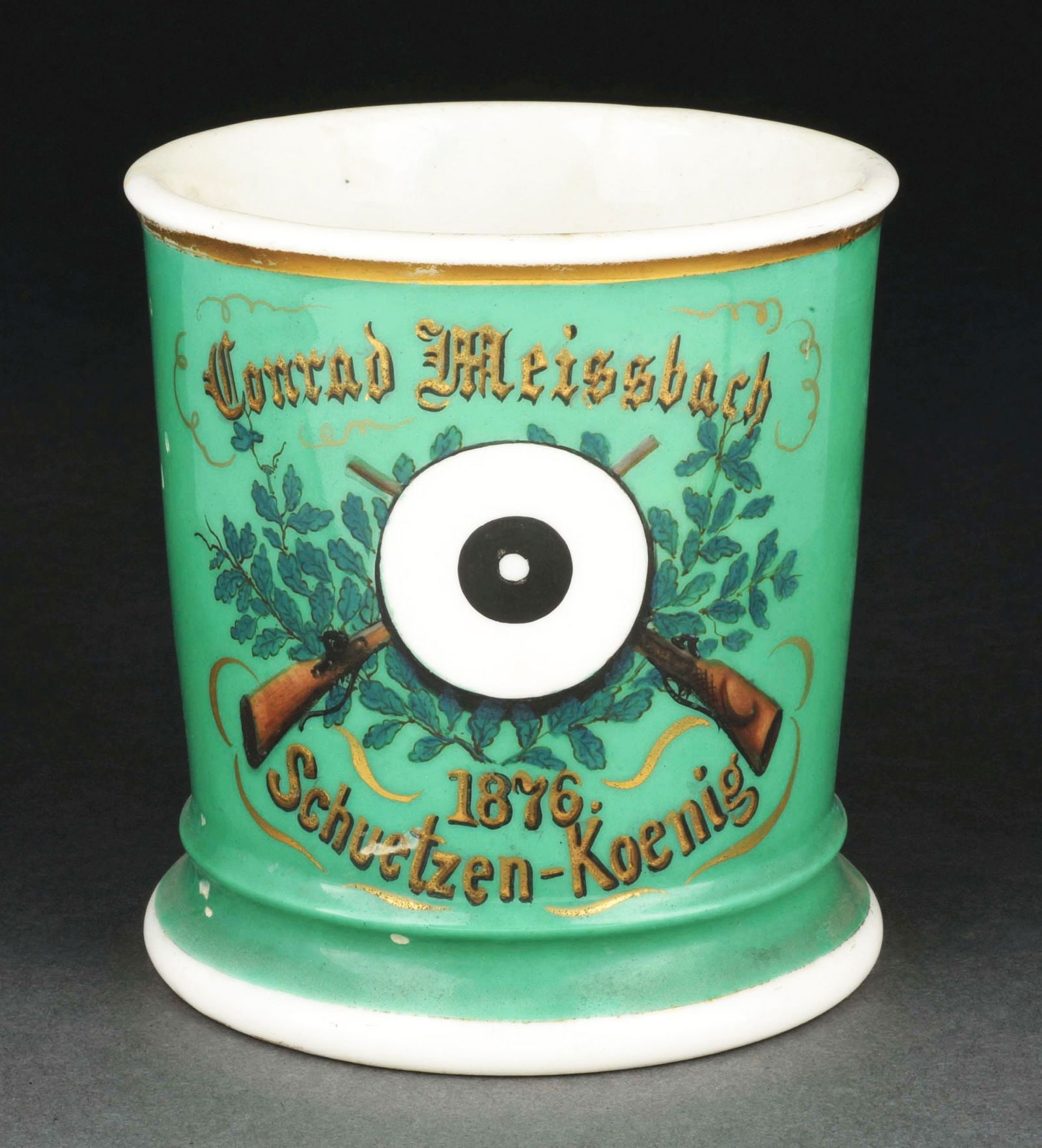 SHOOTERS SHAVING MUG.: Has the name "Conrad Meissbach" in gold gilt, dated 1876. Full green wrap. Nice image of two rifles and a bullseye. Condition: (Excellent). Item Dimensions: 4 - 3/4" x 3 - 3/4" x 3 - 3/4".