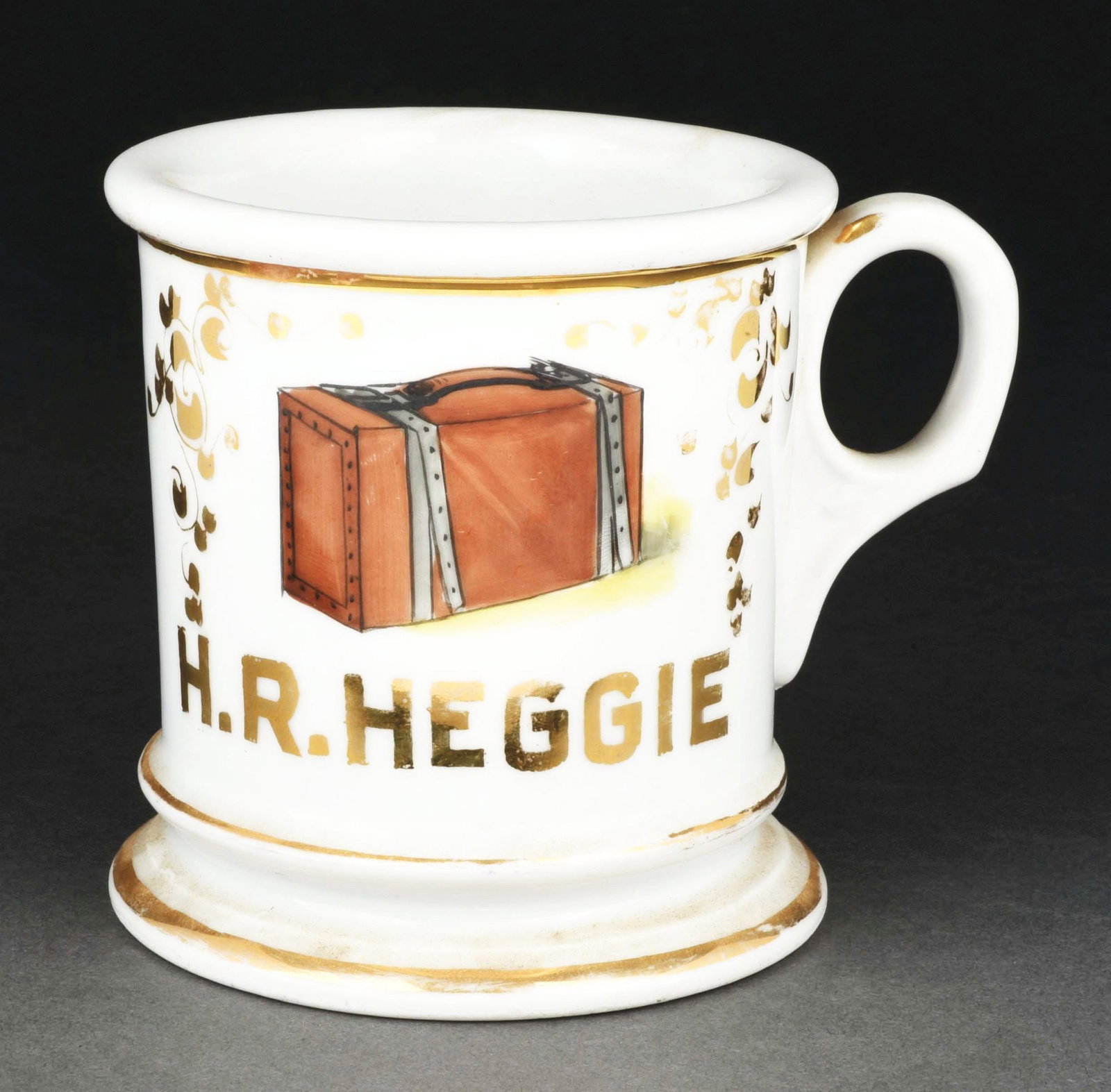 SUITCASE MANUFACTURER SHAVING MUG.: Has the name "H.R. Heggie" in gold gilt across the front. Condition: (Excellent). Item Dimensions: 4 - 1/2" x 3 - 1/2" x 3 - 1/2".