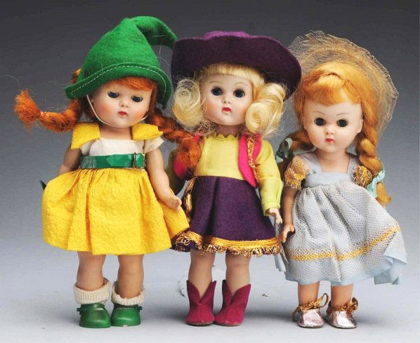 Lot of 3: Hard Plastic “Ginny Dolls".: All marked. Molded lash walker with original tagged cowgirl outfit with hat, cuffs, gun and boots. Strung girl with red braids, tagged yellow and green outfit with hat, belt, shoes and purse, matching