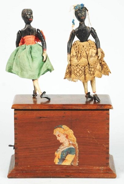 Early Ives Double Dancing Clockwork Toy.: American. Depicts two African American women dancing on top of a wooden box. Original clothing and decal of woman on front of base. Some damage to left hand of one figure. Condition (Very Good - Excel