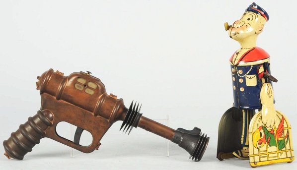 Lot of 2: Toy Character Items.: American. Includes Marx tin litho Popeye walking toy with original pipe and Daisy Buck Rogers Disintegrator pistol. Some scratching and wear to both toys. Condition (Very Good). Size Largest: 10" L.