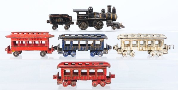 Cast Iron Passenger Train Floor Set.: American. Includes steam engine with cowcatcher, tender with "152" embossed on sides, and three different colored, unmarked passenger cars. Also includes one extra car marked "Transfer". Some paint we