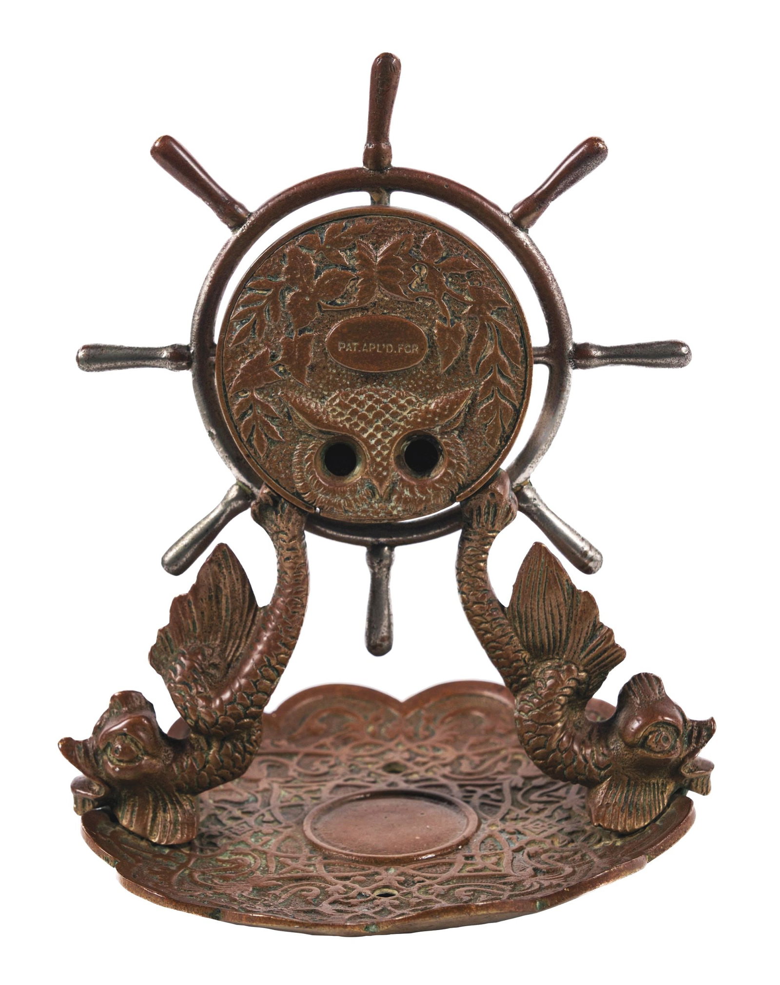 CAST BRONZE DESKTOP CIGAR CUTTER: This desktop cast bronze cigar cutter with a nautical theme, features two dolphins holding a ship's wheel where the cigar cutter is located, attached to an ashtray. The ship's wheel operates via clock