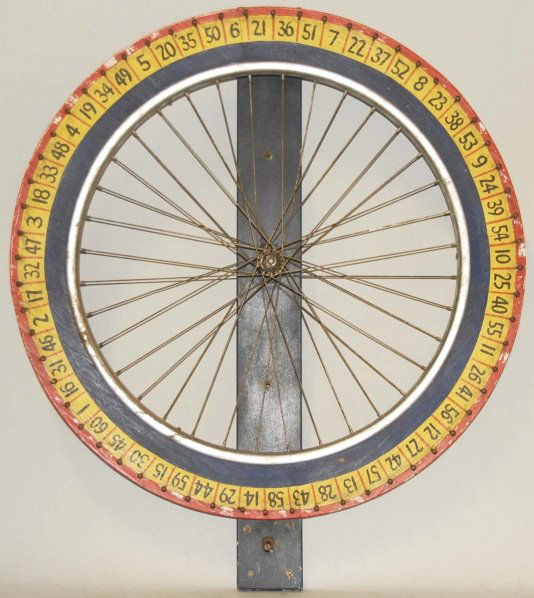 Wooden & Metal Gaming Wheel.: Circa 1950. Consists of a bike wheel with wood surrounding. Moderate wear and soiling. Condition (Very Good). Size 29" Dia.