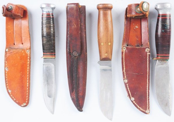 Lot of 3: Marbles Gladstone Sheath Knives.: Includes a "Woodcraft" sheath knife with aluminum crown on stacked leather handle. Knife is in correct Marbles sheath with signed button. Next is an Ideal sheath knife with aluminum crown on stacked l