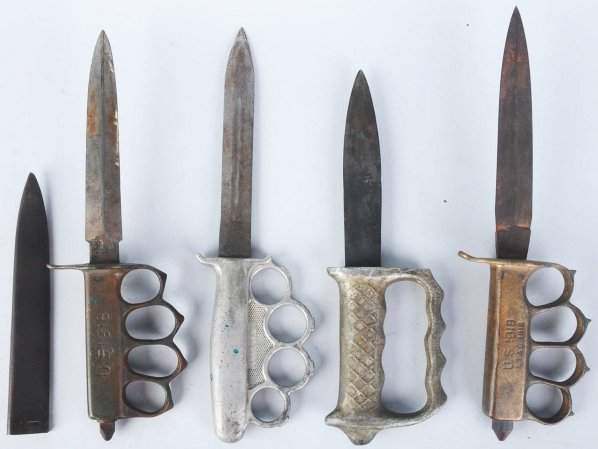 Lot of 4: "Knuckle-Duster" Knives.: Includes one US 1918 L.F. & C. trench knife with brass handle, separate finger holes, and "skull crusher", one US 1918 Au Lion trench knife with brass handle, separate finger holes, "skull crusher", a