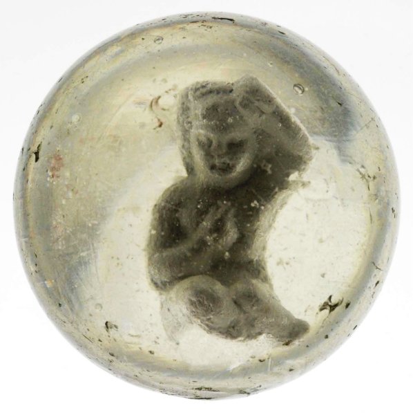 Seated Girl Sulphide Marble.: Depicts a girl seated with one arm on head and the other arm on her chest. Several small chips to surface. Condition (8.7). Size 1 - 11/16"" Dia."