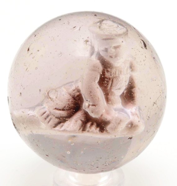 Seated Girl in Dress & Hat Sulphide Marble.: Girl is on knees with legs out and is holding a rubber mallet. Well-centered figure with great detail. Surface has minor chipping and reflections. Condition (8.75). Size 1 - 5/8"" Dia."