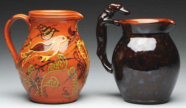Pair of Lester Breininger Redware Pitchers.: Includes one with original hound handle and one with yellow, brown, and green slip decoration of birds and hearts. Condition (Excellent). Size Largest: 9" T.