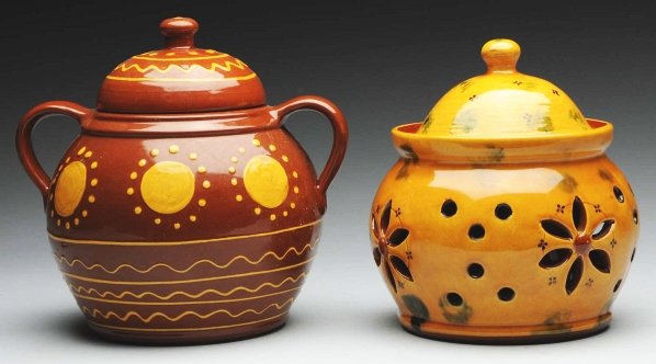 Lot of 2: Lester Breininger Redware Items.: Includes one oversized covered pot with yellow slipware decoration. Also includes one covered jar with distelfink and dot cutouts. Condition (Near Mint Plus). Size Largest: 8" T.