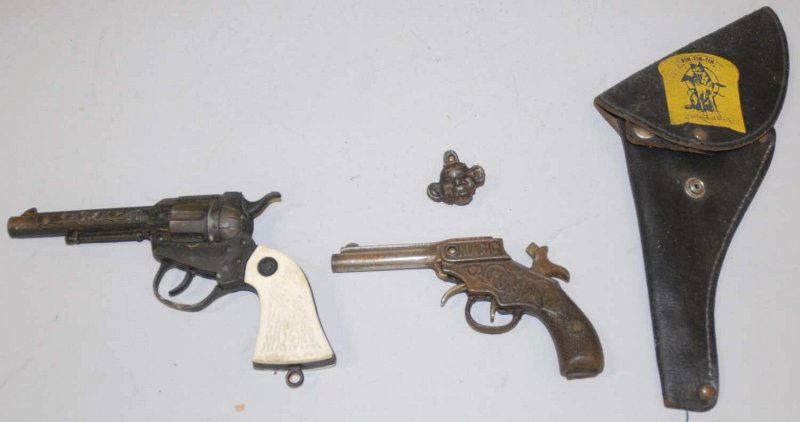 Lot of 2: American Made Cap Guns.: Includes a Rin Tin Tin in original holster and an early cast iron Magic Pistol. Magic Pistol needs spring repair. Both have some pitting and wear. Condition (Good - Very Good). Size Largest: 9" L. Lar