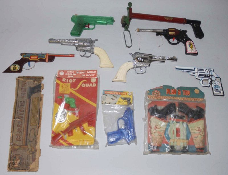 Lot of Miscellaneous Vintage Toy Pistols.: Includes some in tin, plastic, and one made of cardboard that is a clicker toy. Three with original packaging include a double holster cowboy set with darts and a Riot Squad set with badge. Various co