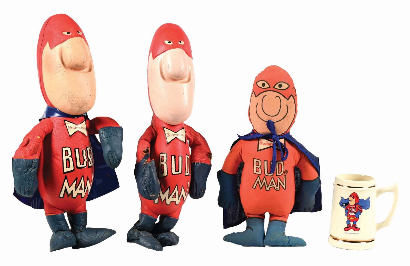 LOT OF 4: BUD MAN DOLLS & MUG: Both the rubber dolls have some overall wear. CONDITION: The one without a cape has some tears to the elbows. There is staining to the stuffed Bud Man. The mug is dated 1987, and is clean overall. Con