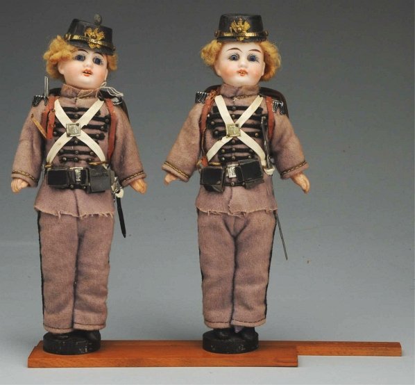 Pair of Twin Prussian Soldier Dolls.: German bisque socket heads incised “56 – 17” made by Gebruder Kuhnlenz, inset glass eyes, open mouths with two square upper teeth, original curly blonde wigs; original papier-mâché bodies with