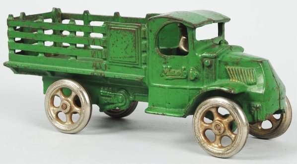 Cast Iron Arcade Mac Front Stake Back Truck Toy.: American. Nickel spoked wheels and original nickel driver. Nice Arcade Toy sticker on driver's side door. Original tin flatbed bottom. Some scratching and wear on roof and bed of truck. Also, some ove