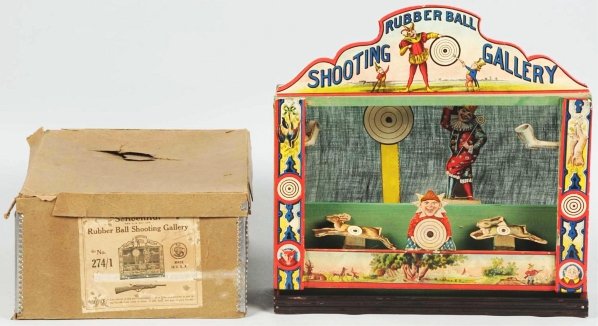 Schoenhut Rubber Ball Shooting Gallery.: German. Nice paper on wood targets showing a hunting scene and two Palmer Cox Brownies on top marquee. Some slight paper peeling on sides. Rifle is missing. Includes original box with nice paper label