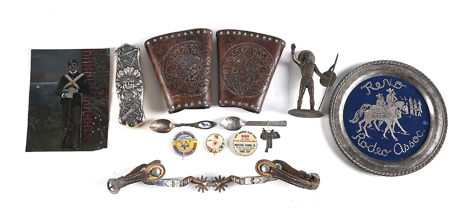 LOT OF MISCELLANEOUS WESTERN MEMORABILIA.: Lot consists of: (A) Western leather studded cowboy cuffs. (B) Set of vintage lady-leg style Texas spurs with straps. (C) 3 celluloid buttons. (D) Saddle watch fob. (E) Two souvenir spoons from the Al
