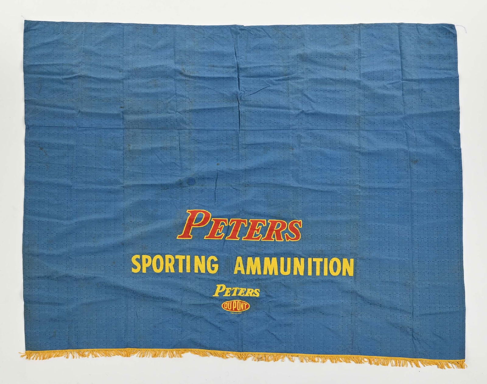 PETERS CARTRIDGE COMPANY TABLECLOTH.: Measures 80" x 62". Blue cloth construction with yellow fringe at bottom. Nice legible graphics. There are a few small tears and holes throughout that do not detract from display. CONDITION: Good.