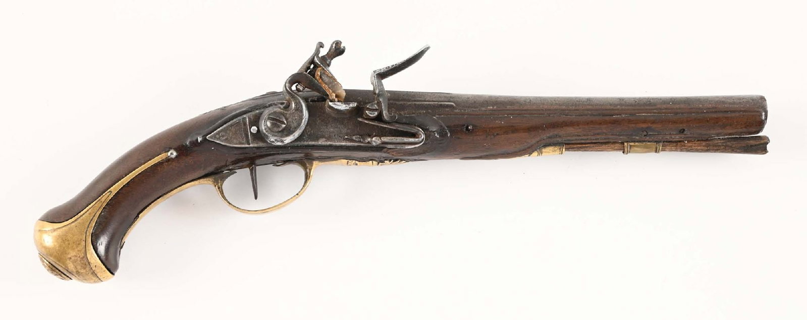(A) A EUROPEAN FLINTLOCK PISTOL IN THE FRENCH TASTE.: Round barrel with flattened sighting rib across top and partially flattened sides at breech. Wooden trumpet ramrod retaned by a faceted balustrade ferrule with with reinforced mouth. Relief carving ar