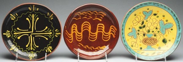 Lot of 3: Lester Breininger Plates.: Largest: 10 - 1/4" Dia. Includes one with slipware decoration, one with blue slipware and large florals in a planter one small glaze chip), and one black slipware decorated plate that is dated "1974".