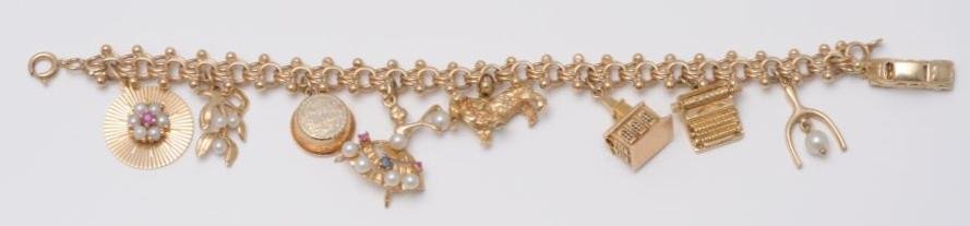 14k Yellow Gold Charm Bracelet.: Bracelet has nine charms, including one church, one typewriter, one car, one ballerina and others. With pearls and rubies. Weight: 26.7 dwt. Condition (Excellent). Size 7" L. CORRECTION: Catalog photo