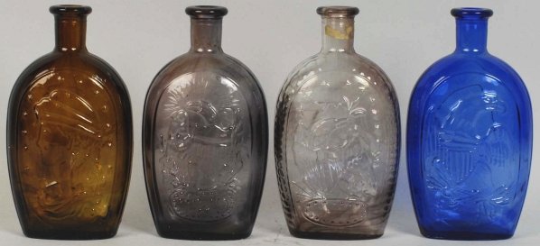 Lot of 4: Colored Glass Flasks.: One in cobalt depicting an eagle, one in Amber glass depicting Miss Liberty and two purple flasks depicting eagles. Condition (Excellent). Size 8 - 3/4" T.