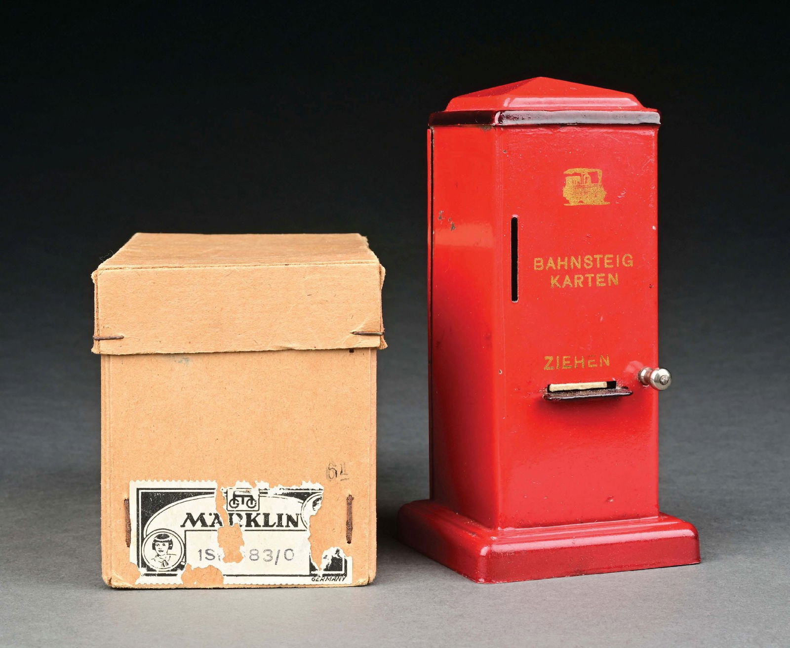 MARKLIN HAND-PAINTED TICKET DISPENSER IN RED W/ ORIGINAL BOX: C. 1930s. CONDITION: In near mint condition. Includes original box. Item Dimensions: 2 - 3/4" x 2 - 3/4" x 5 - 1/2".