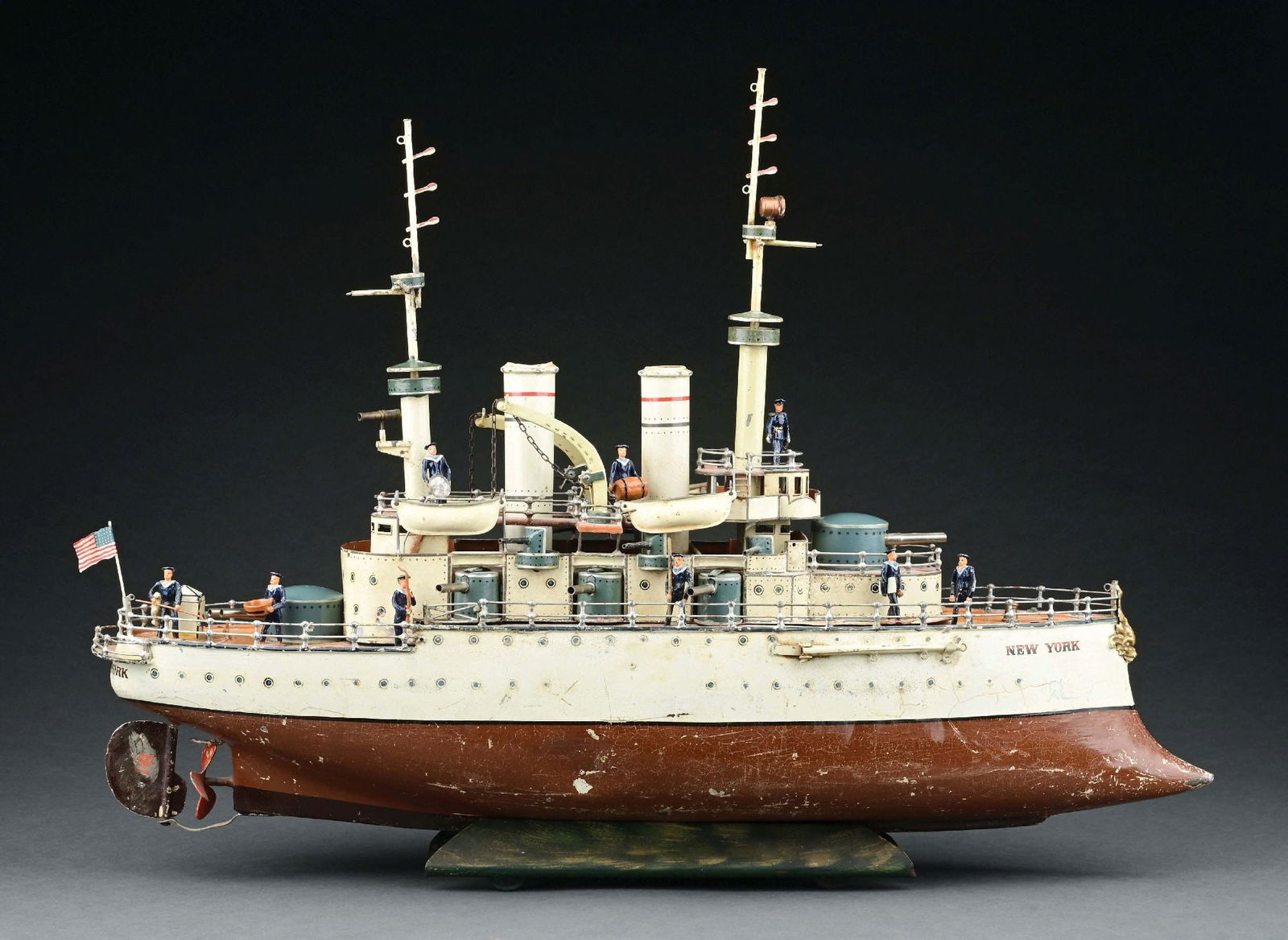 MARKLIN CAT. REF. 5121 "NEW YORK" BATTLESHIP W/ CLOCKWORK POWER: CONDITION: Replacement flag, four replaced life boats, bow mast replaced, front and rear gun turret covers restored, as well as the two cranes and the hull swing bay arms, locking anchor. Lower brown