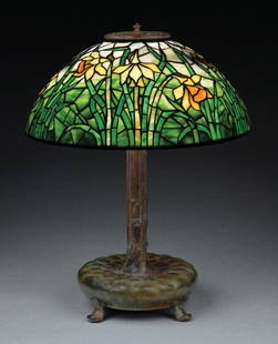 TIFFANY STUDIOS DAFFODIL LEADED GLASS TABLE LAMP: A lovely example of a 16" daffodil table lamp by Tiffany Studios. The 16" diameter shade features the windswept daffodil motif with a background of beautiful streaked green glass, progressing to white