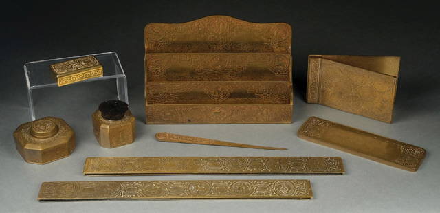 TIFFANY STUDIOS 9-PIECE ZODIAC DESK SET: A lovely 9-piece desk set by Tiffany Studios. The set is finished in a gold dore with the Zodiac pattern. The set includes two blotter ends, letter opener, stamp box, notepad holder, stand with brush,