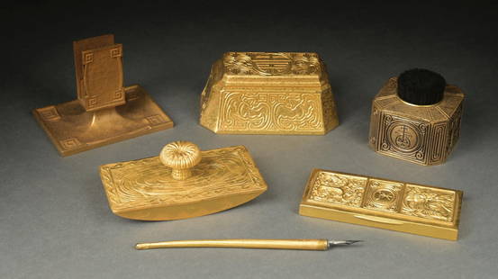 LOT OF 6: TIFFANY STUDIOS 6-PIECE DESK SET IN GOLD: A lovely 6-piece desk set by Tiffany Studios. All six pieces are finished in a beautiful gold dore in various patterns. The set includes: a pen brush (973), a pen, rocker blotter (1846), a paperweight
