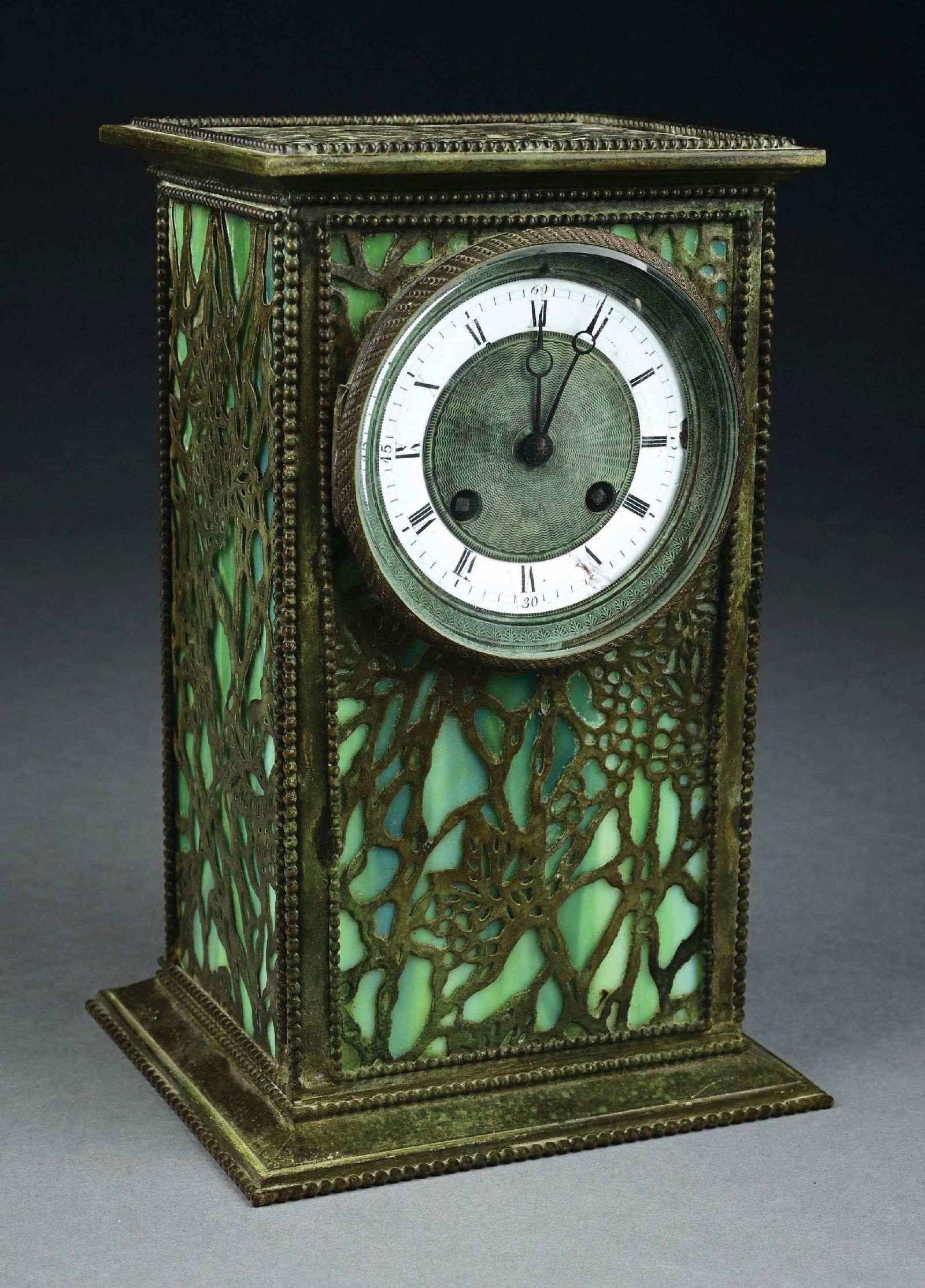RIVIERE OVERLAY CLOCK: A beautiful slag glass and overlay clock by Riviere Studios. The clock has a white circular face and green slag glass panels, with patinated filigree. The clock is in very good condition, with no dama