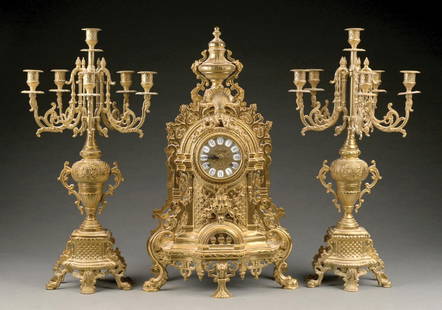 3-PIECE ITALIAN BRASS BAROQUE MANTEL CLOCK GARNITURE: C. 1910. Three-piece gilt bronze clock garniture comprising a mantel clock and matched pair of figural tabletop candelabra, clock having Franz Hermle (Germany) movement and Imperial clock face marked