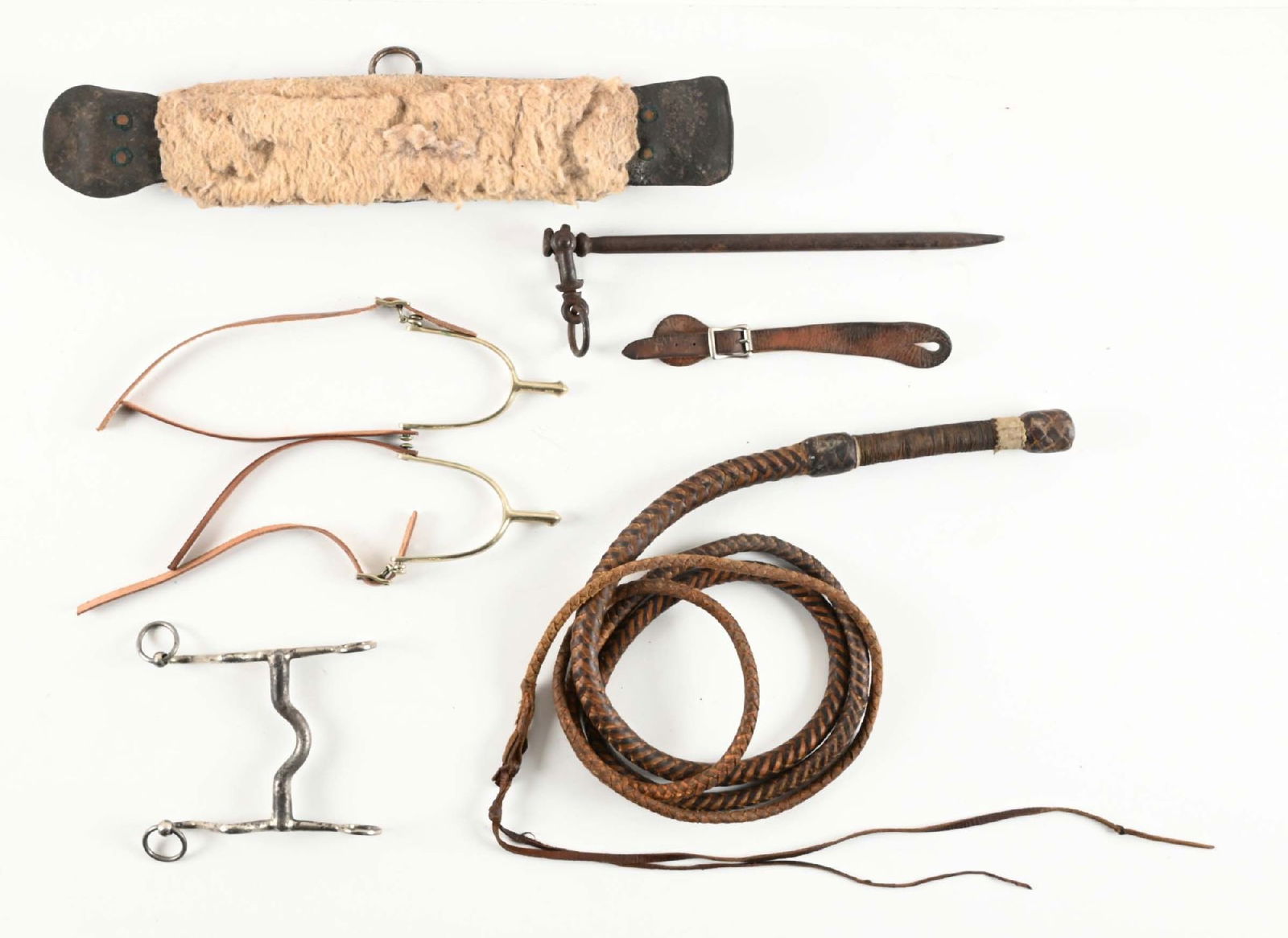ASSORTED WESTERN TACK AND ACCOUTREMENTS.: Lot of antique riding gear. Includes 1892 U.S. marked curb bit, braided bullwhip, cinch strap, cavalry picket pin, August Buermann World War I-era US contract spurs, and an early English style saddle