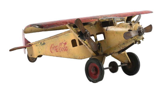 TIN TOY COCA-COLA AIRPLANE MODEL: C. 1930s lithographed steel tin toy airplane featuring Coca-Cola branding and Coca-Cola script. CONDITION: Original paint with paint loss, scratching, some touch-up paint and repair throughout. Condit