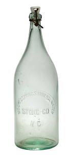 MOORE'S SPRINGS MINERAL WATER BOTTLE: Scarce bottle featuring a mid-body round slug plate, embossed with "MOORE'S SPRINGS MINERAL WATER STOKE CO. / N.C.". CONDITION: Bottle features it original porcelain top and metal closure. There is so