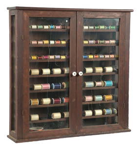 COUNTERTOP/WALL MOUNT THREAD DISPLAY CABINET: C. 1920. CONDITION: It shows all original wood construction with interior spool display. It is in all original finish, showing some scuffs and scrapes. The glass panel to the right side shows an area