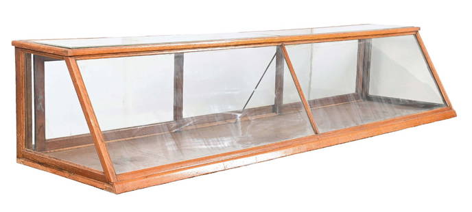 OAK SLANT-FRONT COUNTRY STORE PASTRY CASE: C. 1910. CONDITION: Showing oak construction with all original glass. Top glass is beveled. Original sliding rear doors. Showing areas of wear, scuffs, scrapes, and scratches, both to the glass and to