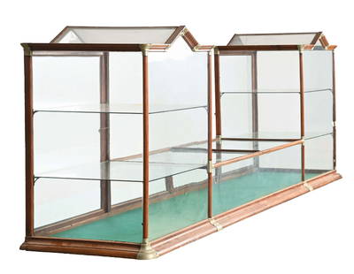 LARGE DOUBLE-STEEPLE SHOWCASE IN OAK W/ BRASS CORNERS: C. 1910. Maker marked "Claes & Tennbeuter, St. Louis, Missouri". CONDITION: Showing all original brass corners intact. All original glass, original back doors, and original interior shelves. Light are