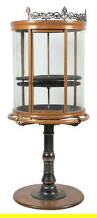 ROUND REVOLVING "CRYSTAL" SHOWCASE ON ORIGINAL STAND: C. 1910. Crystal Showcase Co. CONDITION: All original showing scratches and scuffs to the original finish, some oxidation and missing paint to the cast iron base. The top cast bronze gallery has sever